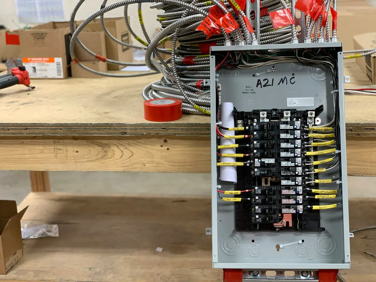 Breaker panel wired with armored cable on a workbench